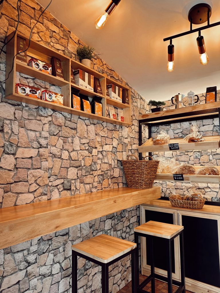 Warm interior of a rustic cafe featuring stone walls and wooden furniture.